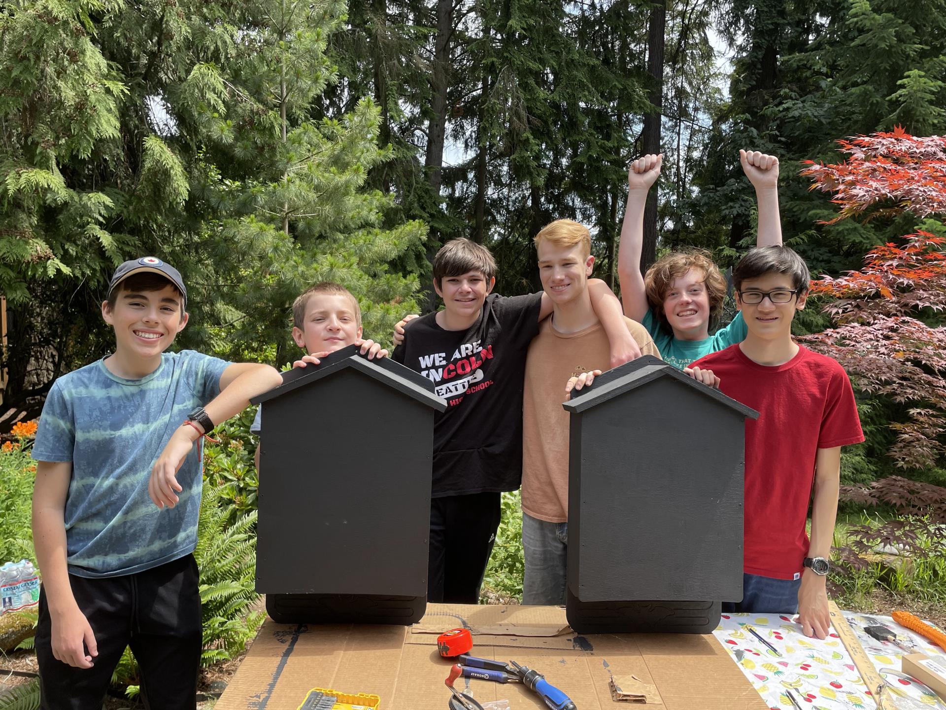 Volunteers standing behind two bat boxes they assembled and painted black.