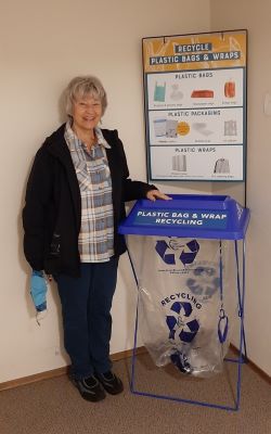 A resident standing near a plastic bag recycling station.