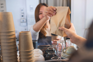 Restaurant worker handing a customer their takeout order.