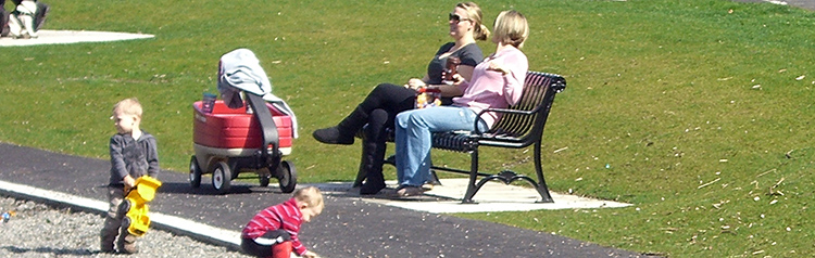 Two women sit on a bench at Echo Lake Park while their toddlers play